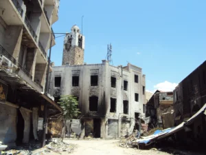 مشهد من شارع الدالاتي نحو الجنوب يظهر الأضرار المحيطة ومئذنة جامع النوري، حمص