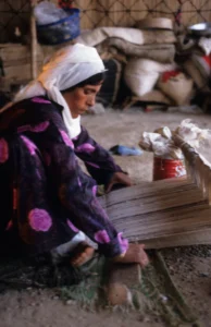 A Bedouin woman is weaving with a horizontal loom