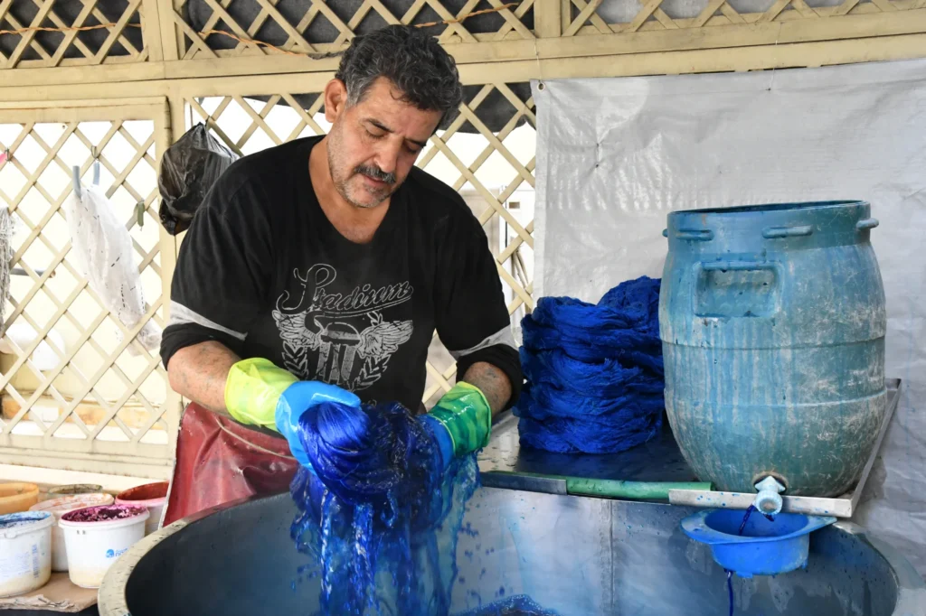 Seidenfäden werden in kochendem Wasser blau gefärbt. Dieser Prozess wird mehrere Male wiederholt bis die Seide die blaue Farbe vollständig aufgenommen hat