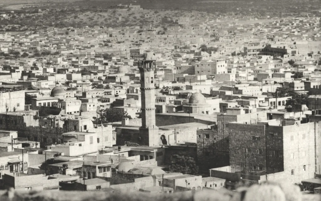 Historical photograph of the Mamluk Jamiʿ Altunbugha. The octagonal minaret clearly towers above the predominantly traditional buildings in the ancient city quarter of al-Aʿjam